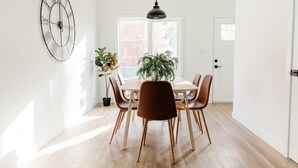 Un coin repas avec une table et des chaises en bois, une plante en pot et une horloge murale.