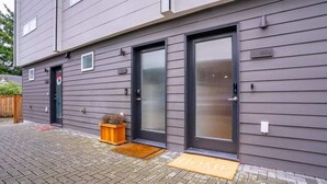 A modern building with grey siding, two front doors, and a small wooden planter.