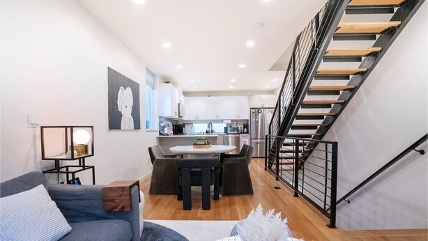A modern apartment with a kitchen, dining area, and a staircase.
