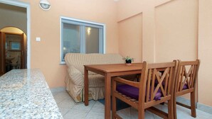 A compact living space with a kitchenette, a dining area with a wooden table and chairs, a window, and a small potted plant.