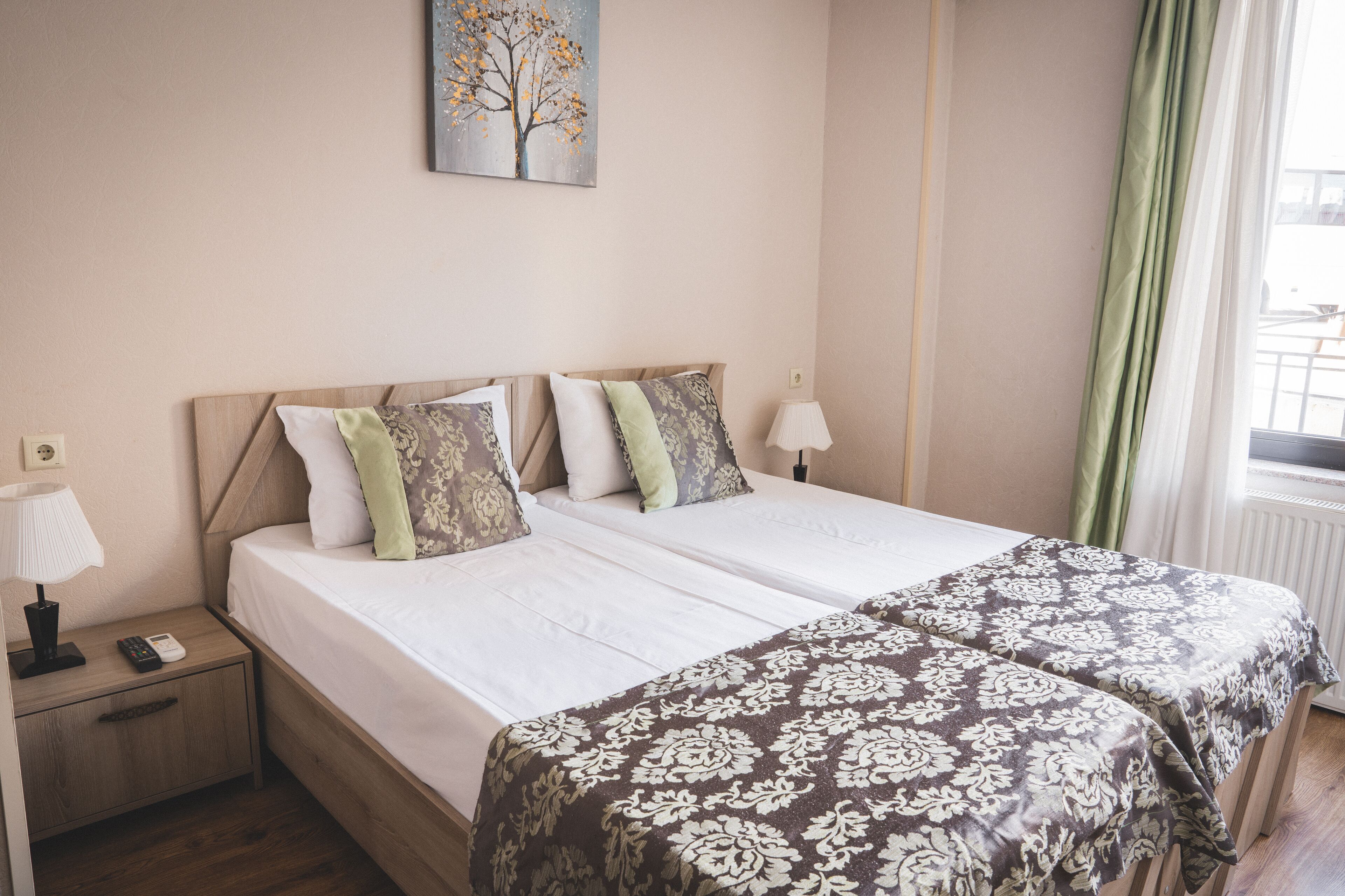 A double bed with a wooden headboard, two bedside tables, a lamp, and a painting on the wall.