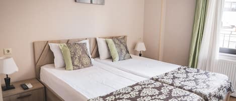A double bed with a wooden headboard, two bedside tables, a lamp, and a painting on the wall.