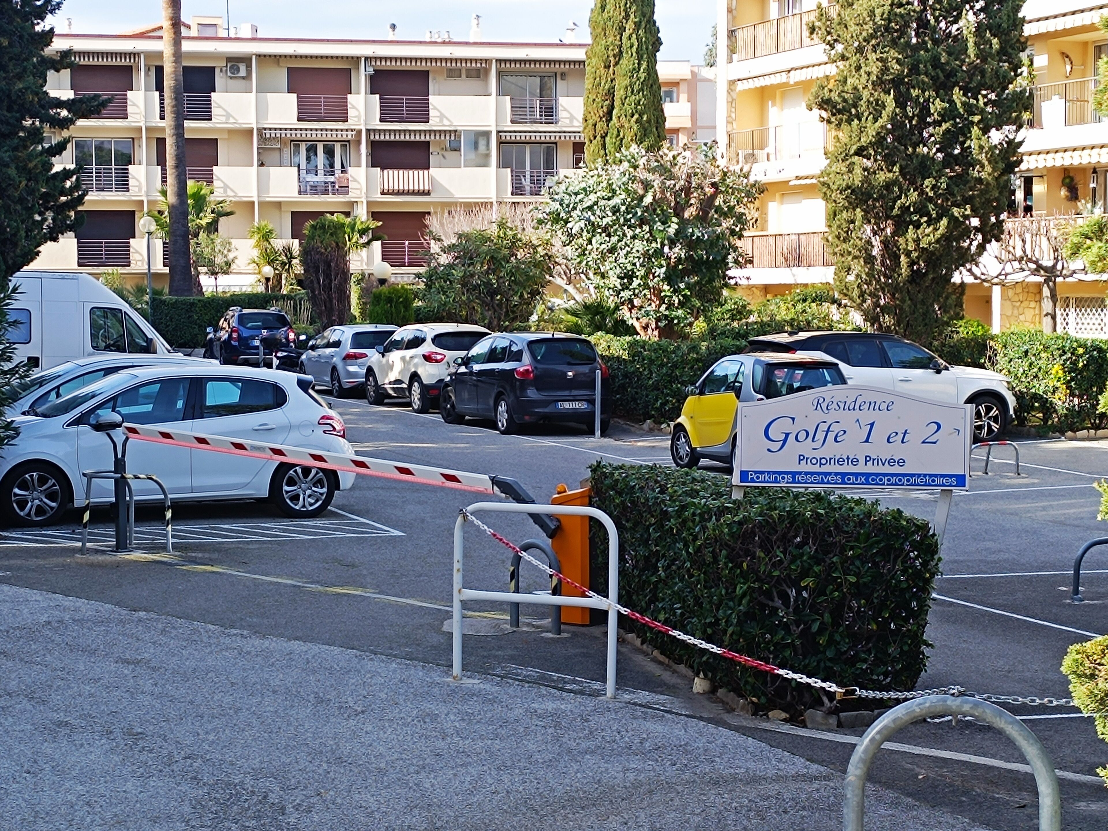 A gated parking area with a sign indicating 'Residence Golfé 1 et 2' and 'Propriété Privée'.