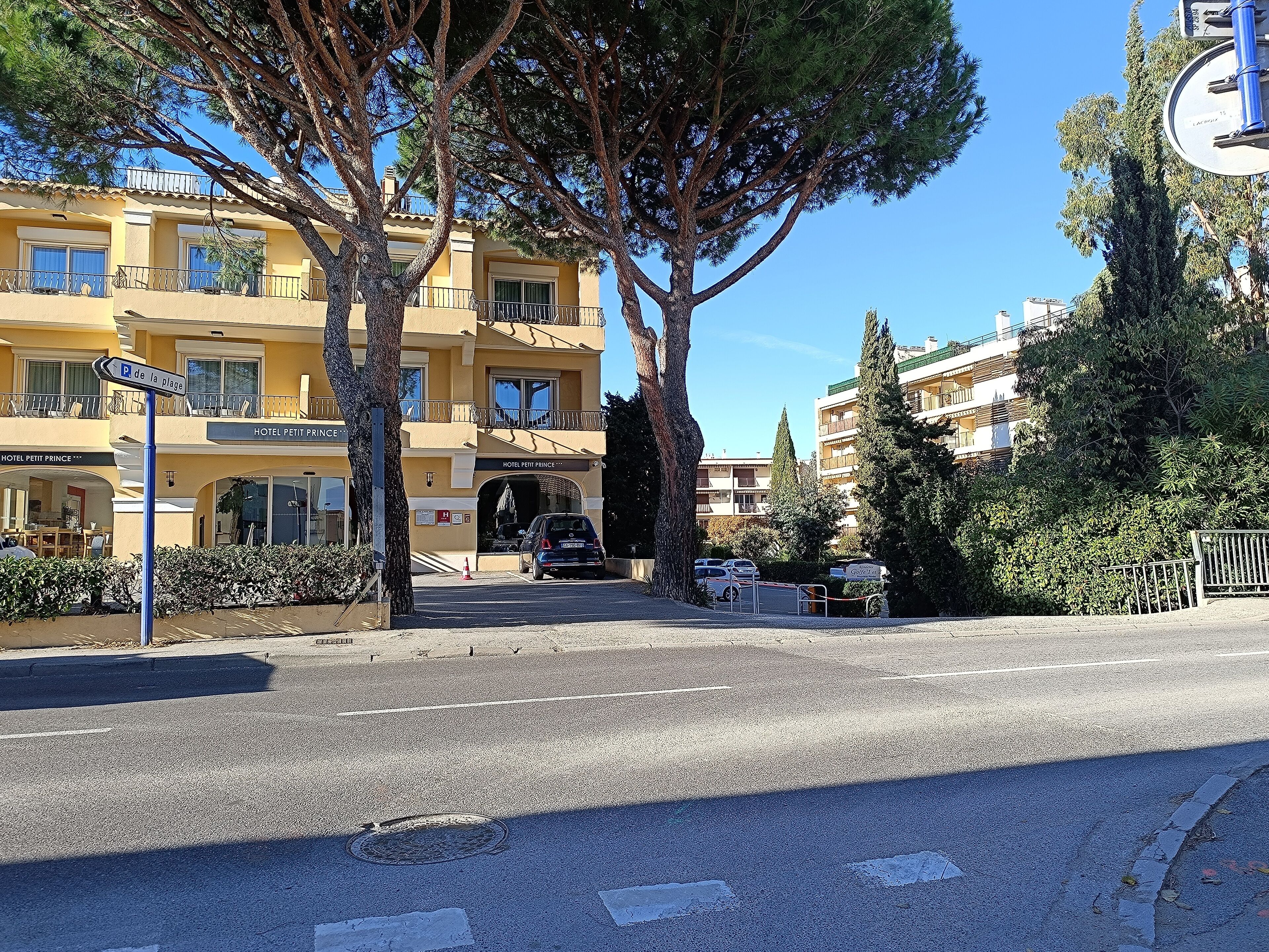 A hotel named "Hotel Petit Prince" with a yellow facade, balconies, and a parking area.