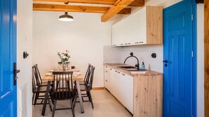A compact kitchen with wooden beams, a blue door, and a dining area with chairs and a table. - Gorgeous home in Rowy with house a panoramic view (Rowy)