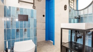 A bathroom with a white toilet, a sink with a black faucet, and blue-tiled walls. - Gorgeous home in Rowy with house a panoramic view (Rowy)