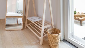 Ein Zimmer mit Holzbalkendecke, einem großen Spiegel, einem Wäscheständer aus Holz und einem Korbwäschesammler.