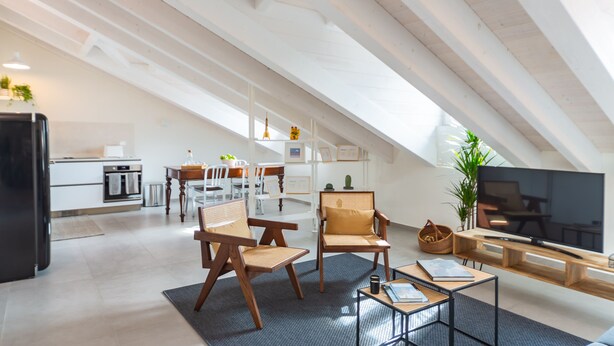 Ein geräumiges Loft mit hohen Decken, einer Küchenzeile und einer Sitzecke mit Fernseher.
