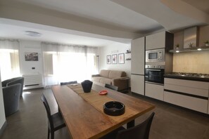 Une cuisine moderne avec un coin repas, comprenant une table en bois, des chaises, un four à micro-ondes et un four traditionnel.