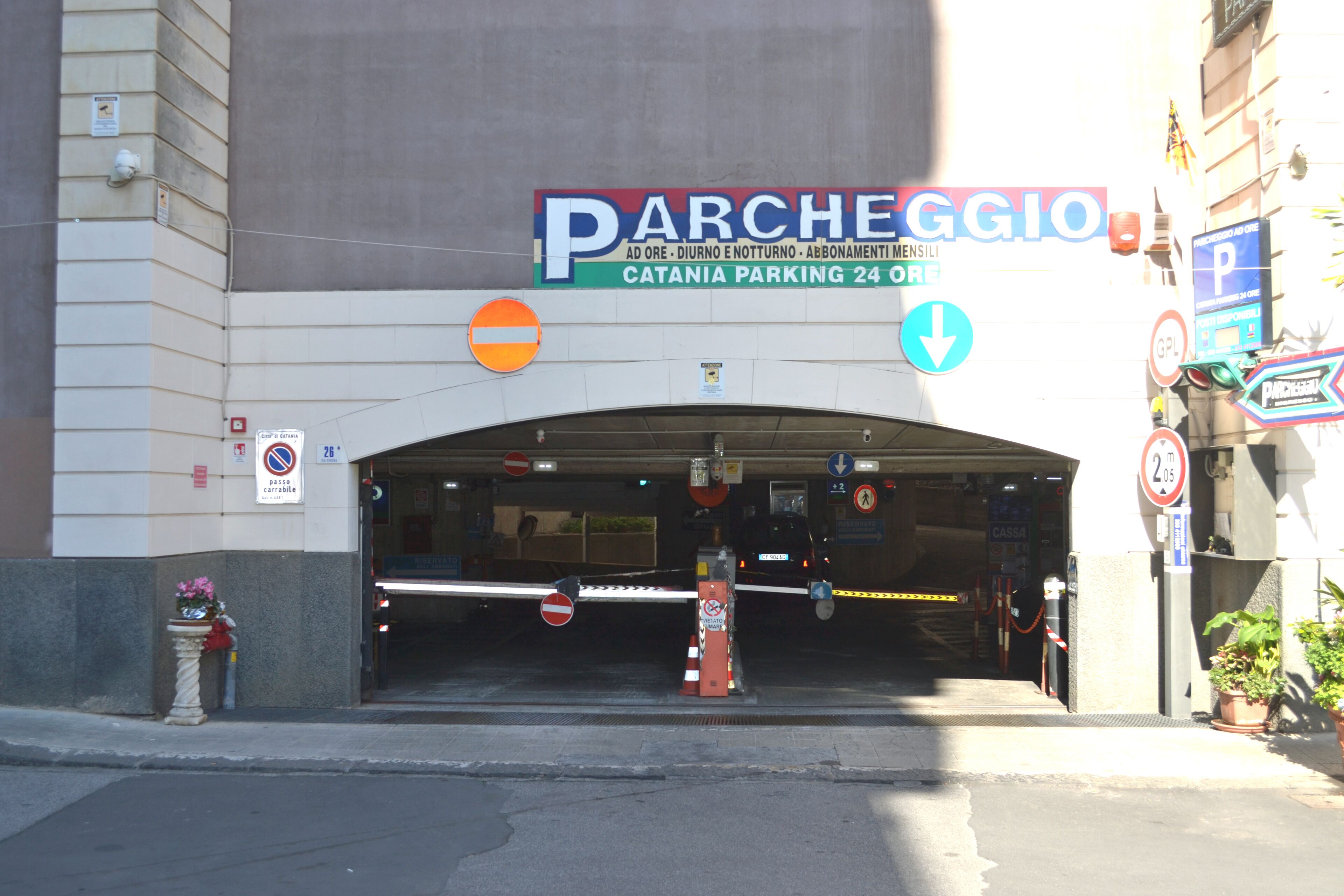 Ingresso di un parcheggio con un cartello che indica 'Parcheggio' e servizio attivo 24 ore.