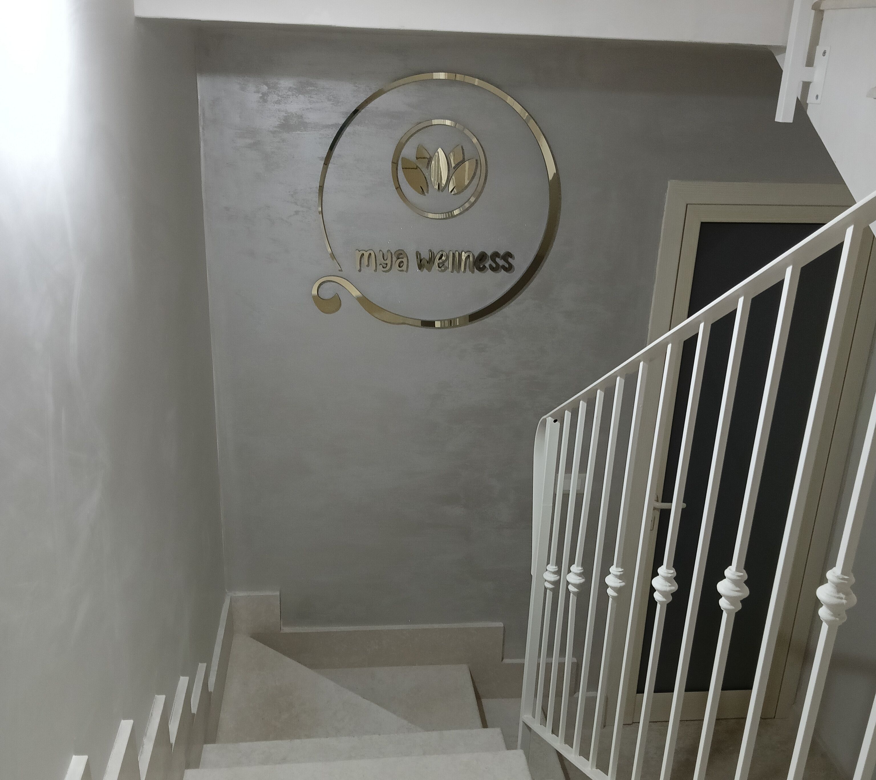 Un escalier avec une rampe blanche et une enseigne fixée au mur sur laquelle on peut lire : « Mon espace bien-être ».