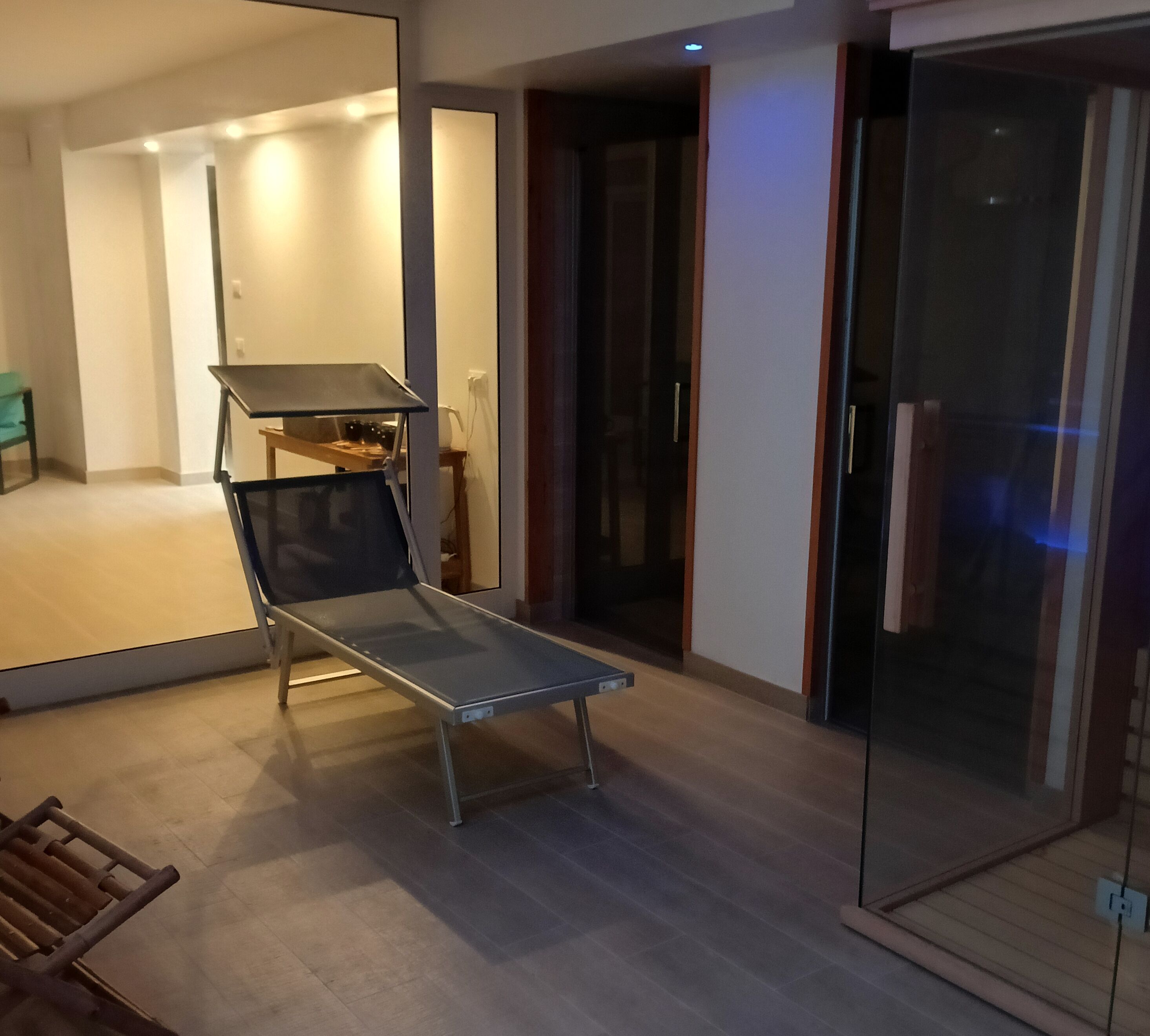 A modern living room with a glass partition, a small table, and a chair.