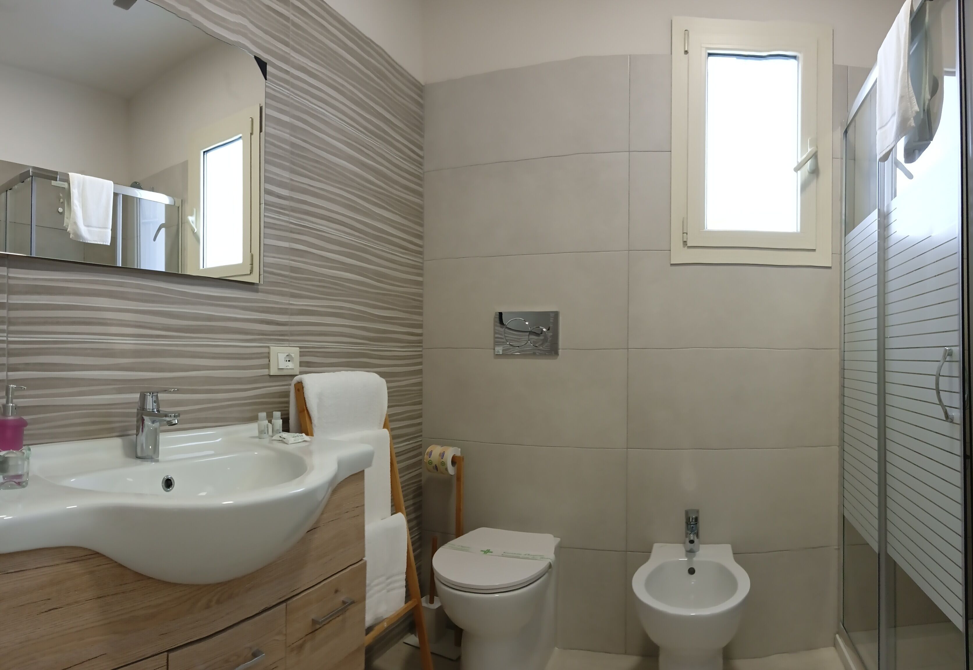 Une salle de bain équipée d’un lavabo, de toilettes, d’un bidet et d’une fenêtre.