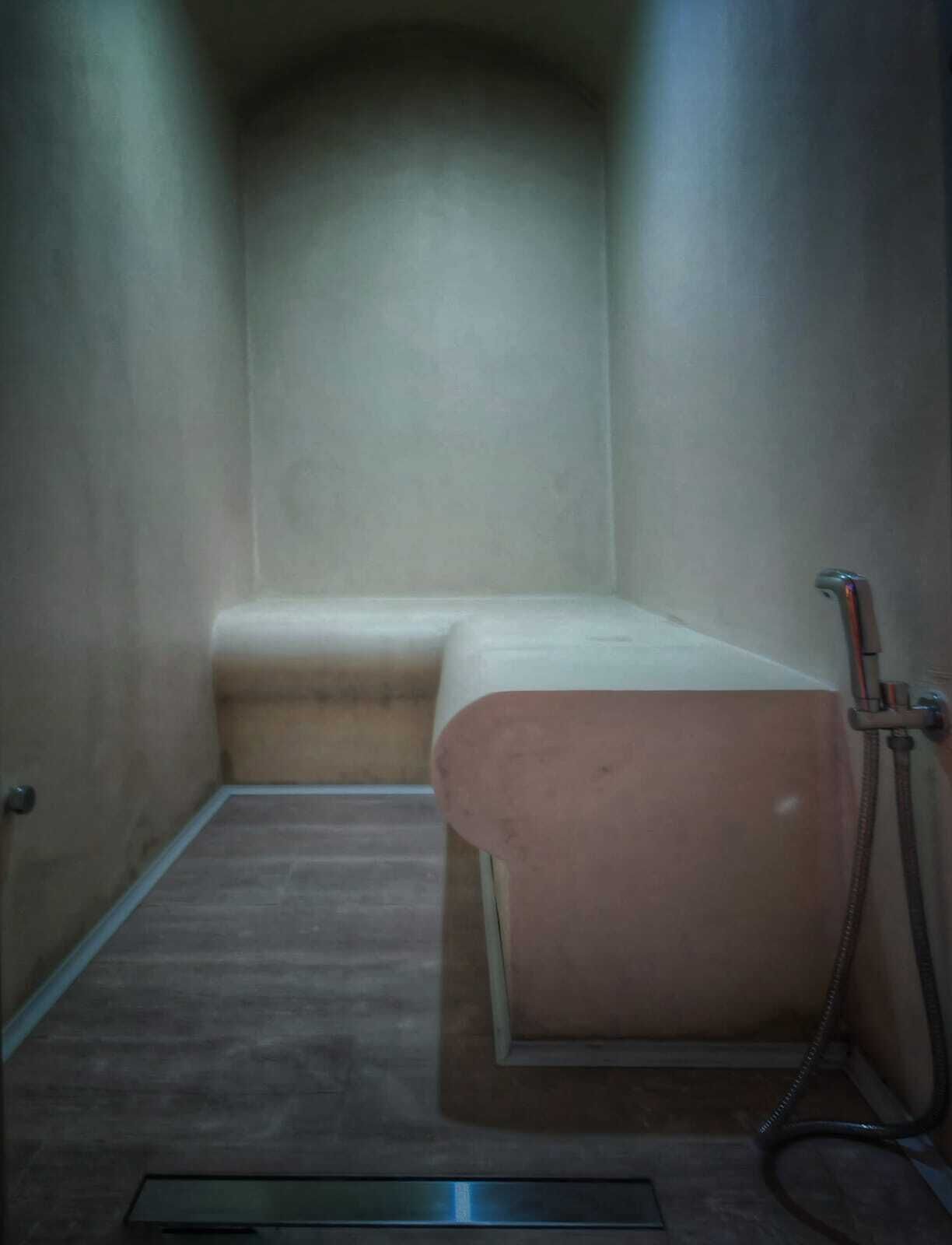Una habitación pequeña y estrecha con una banca y una ducha.