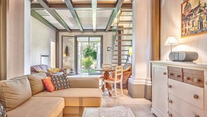 A spacious living area with a sofa, chairs, a dining table, and a cabinet. A staircase leads to an outdoor area. - Villa Church with private pool - My Rental Homes (Cortona)