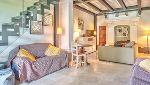 A hotel room with a modern design, featuring a glass staircase, a sofa, a dining area, and a television. - Villa Church with private pool - My Rental Homes (Cortona)
