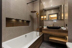Ein modernes Badezimmer mit Badewanne, Dusche und Waschtisch mit Spiegel.