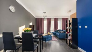Una sala de estar moderna con comedor, un conjunto de sofás y una estantería.