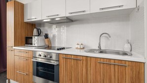Una cocina moderna con armarios de madera, electrodomésticos de acero inoxidable y encimera blanca.