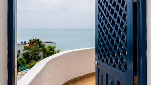 A view through an open door to a balcony with a tiled floor, overlooking a body of water and buildings. - Excelente vista Casa Blanca - Same  (Tonchigüe)