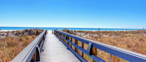 A wooden boardwalk leading to a beach with clear skies.