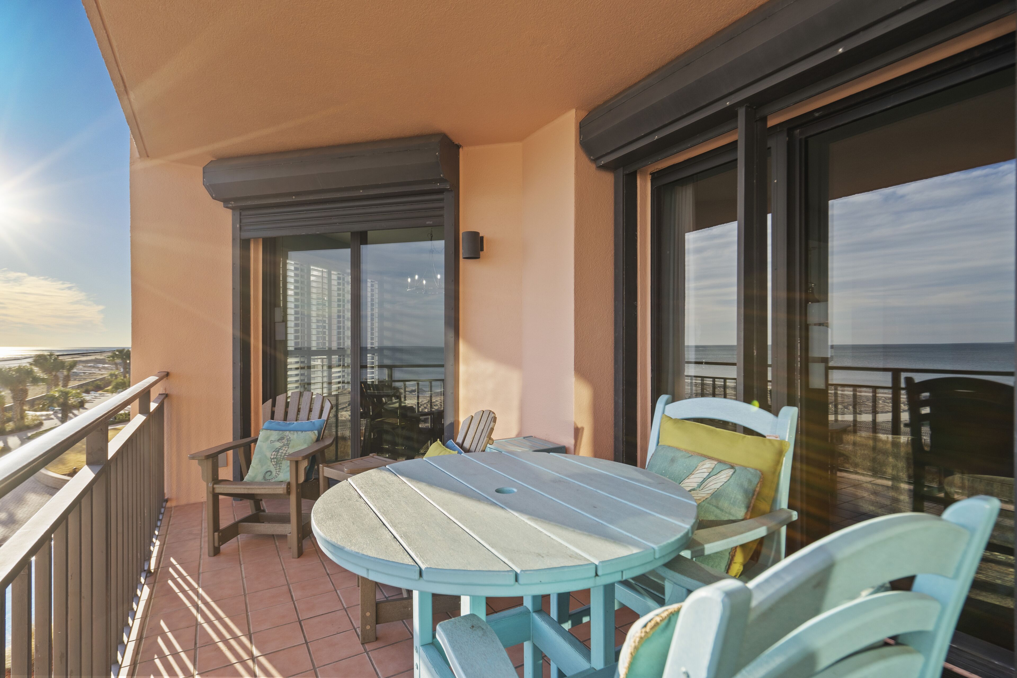 A balcony with a round table and chairs, a view of the cityscape, and a railing.