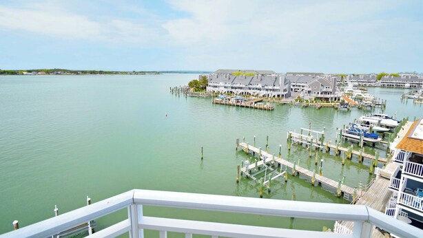 A marina with docked boats, a pier, and buildings with balconies overlooking the water. - Bahia Vista I 508-Baywater 10th St, Free WiFi, Pool, Elev, W/D, AC (Ocean City)