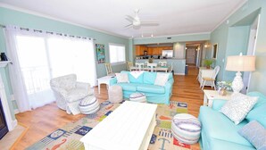 A spacious living room with a teal sofa, a patterned rug, and a white coffee table. - Bahia Vista I 508-Baywater 10th St, Free WiFi, Pool, Elev, W/D, AC (Ocean City)
