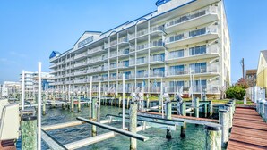 A multi-story hotel with balconies, a dock, and a clear blue sky. - Bahia Vista I 508-Baywater 10th St, Free WiFi, Pool, Elev, W/D, AC (Ocean City)