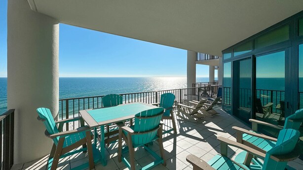 A balcony with a table and chairs, overlooking the ocean. - Beachfront!! Lazy River and Slide!!  New Rental!! (Orange Beach)