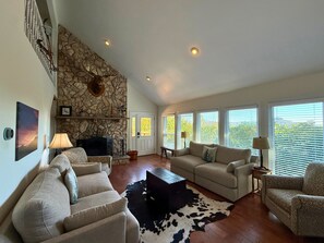 A living room with a stone fireplace, a sofa, a coffee table, and a cowhide rug. - Beautiful 3 bedroom mountain home with views of Grandfather Mountain (Sugar Mountain)