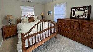 Un dormitorio con una cama de madera, dos mesitas de noche, un aparador y una lámpara en el techo.