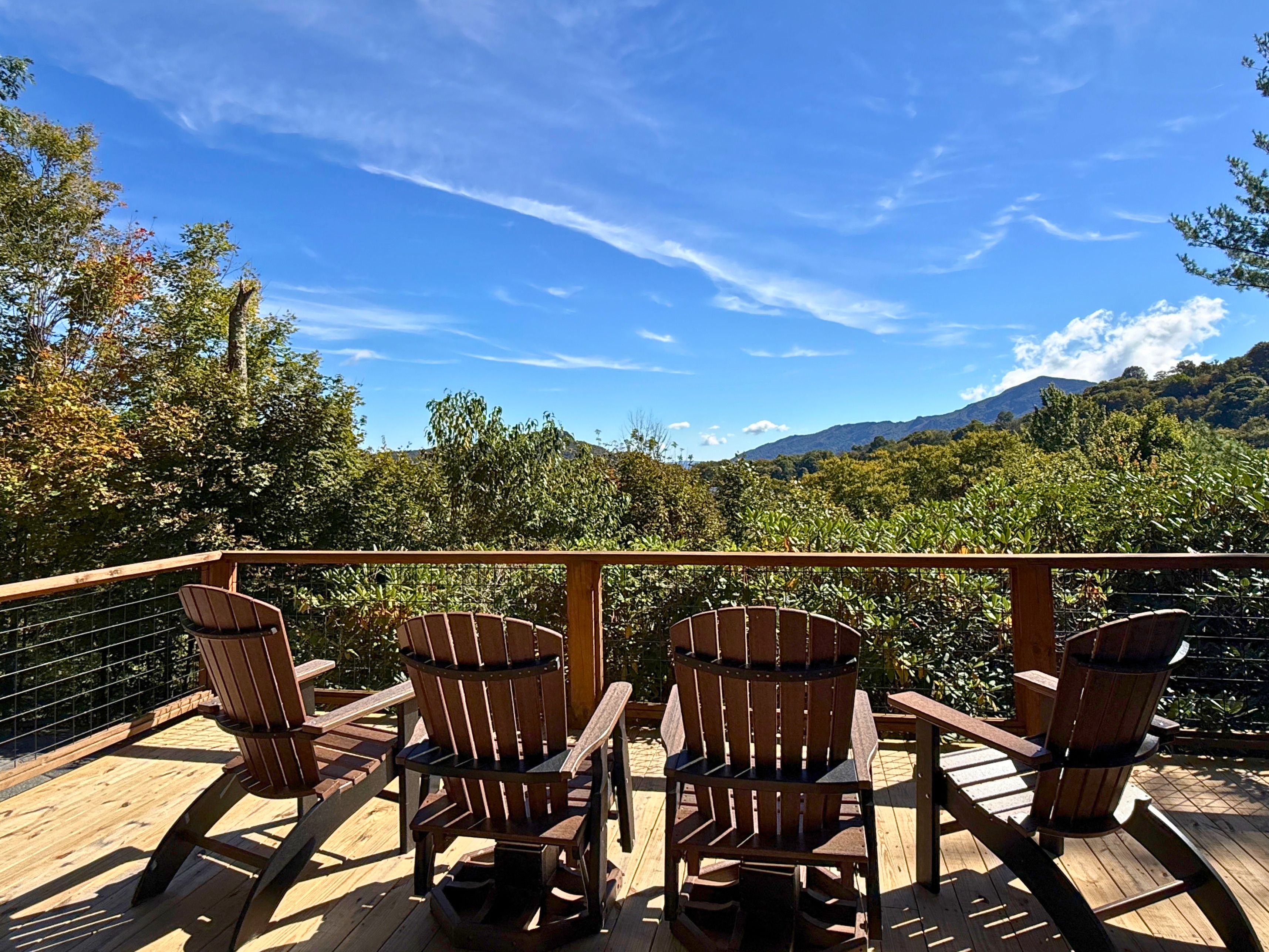 Une terrasse dotée de chaises et de tables en bois, offrant une vue sur un paysage montagneux.