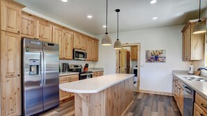 Une cuisine moderne avec des meubles en bois, des appareils électroménagers en acier inoxydable et un îlot central.