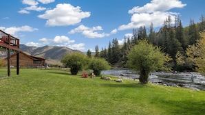 Eine Lodge mit Holzfassade, einer Terrasse und Blick auf einen Fluss.