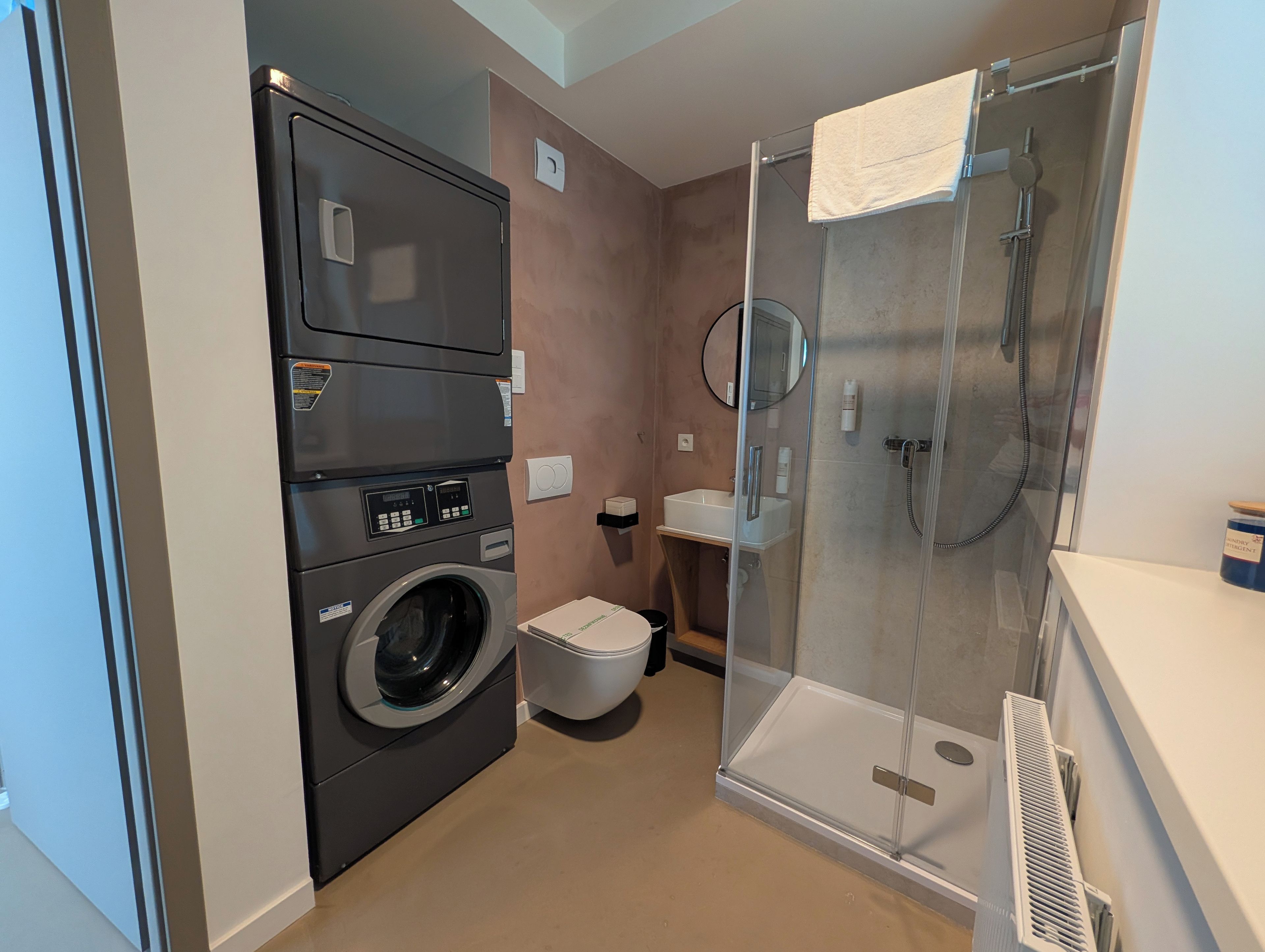Ein kleines Badezimmer mit Waschmaschine, Toilette, Duschkabine und Waschbecken.