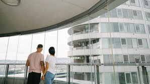 A modern building with a curved glass facade and a view of a cityscape. - Slavic Industrial Apartment by CHORS (Bratislava)
