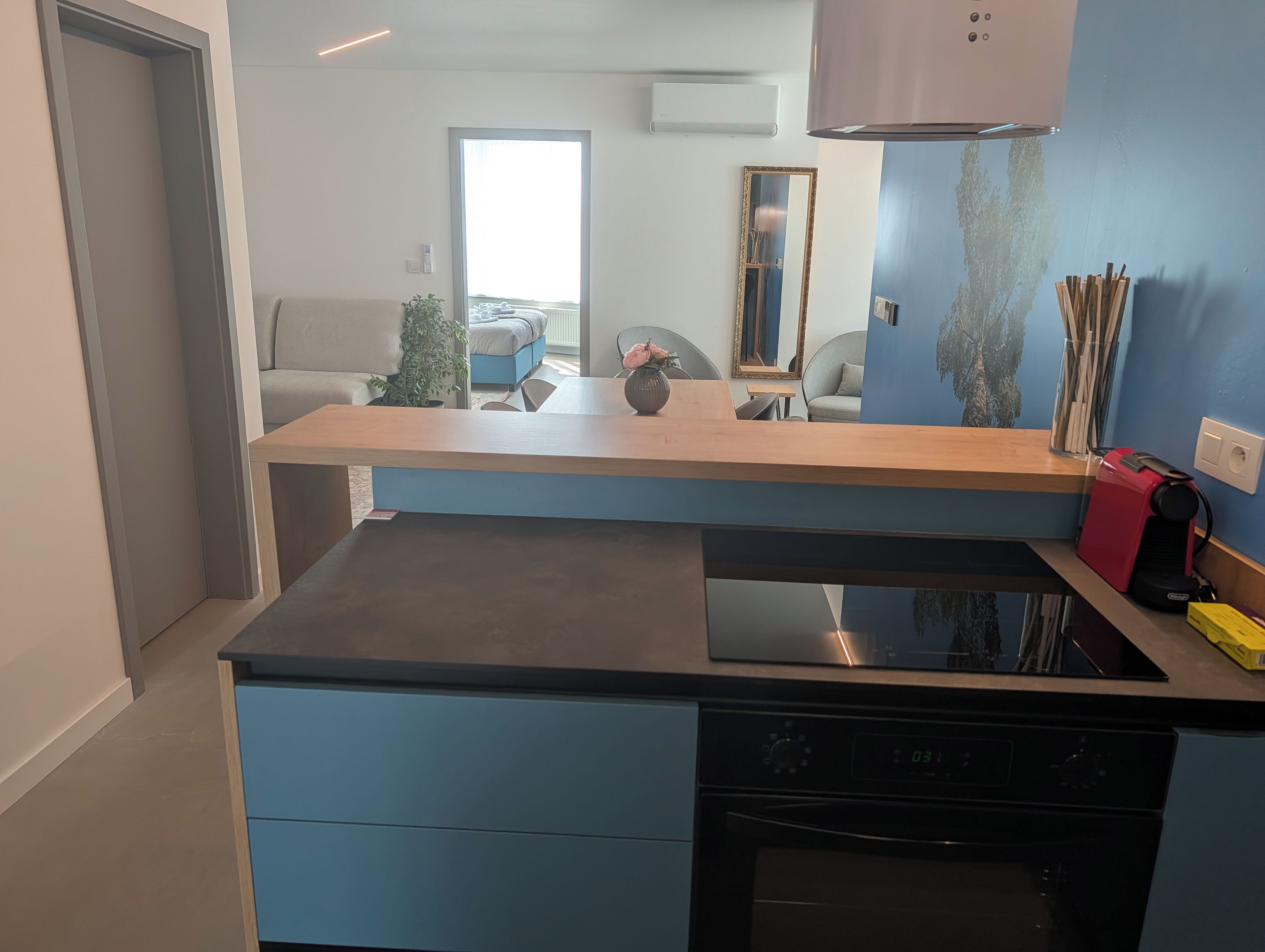 Eine moderne Küche mit eingebautem Herd, einer Holz Arbeitsplatte und einem blauen Schrank.