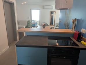 A modern kitchen with a built-in stove, a wooden countertop, and a blue cabinet.