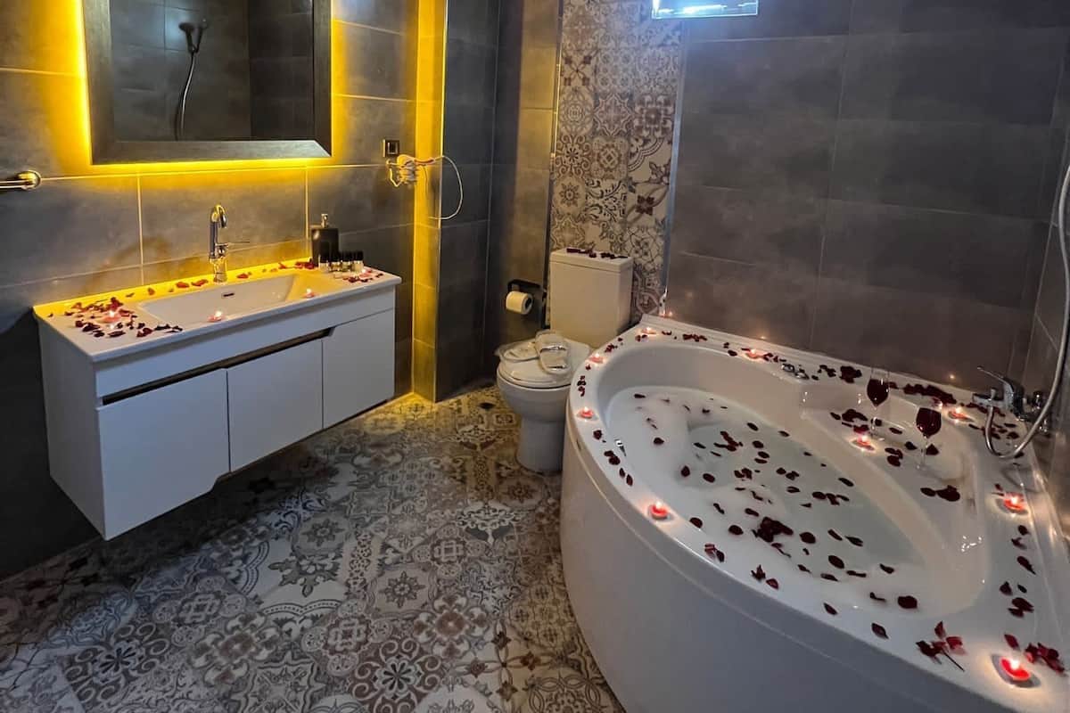 A modern bathroom with a large bathtub, a double sink vanity, and a toilet.
