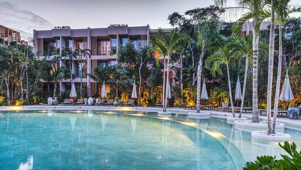 A swimming pool surrounded by lounge chairs and umbrellas, with a building in the background. - Stunning Studio Tulum Jungle w/ Pool Restaurant (Tulum)