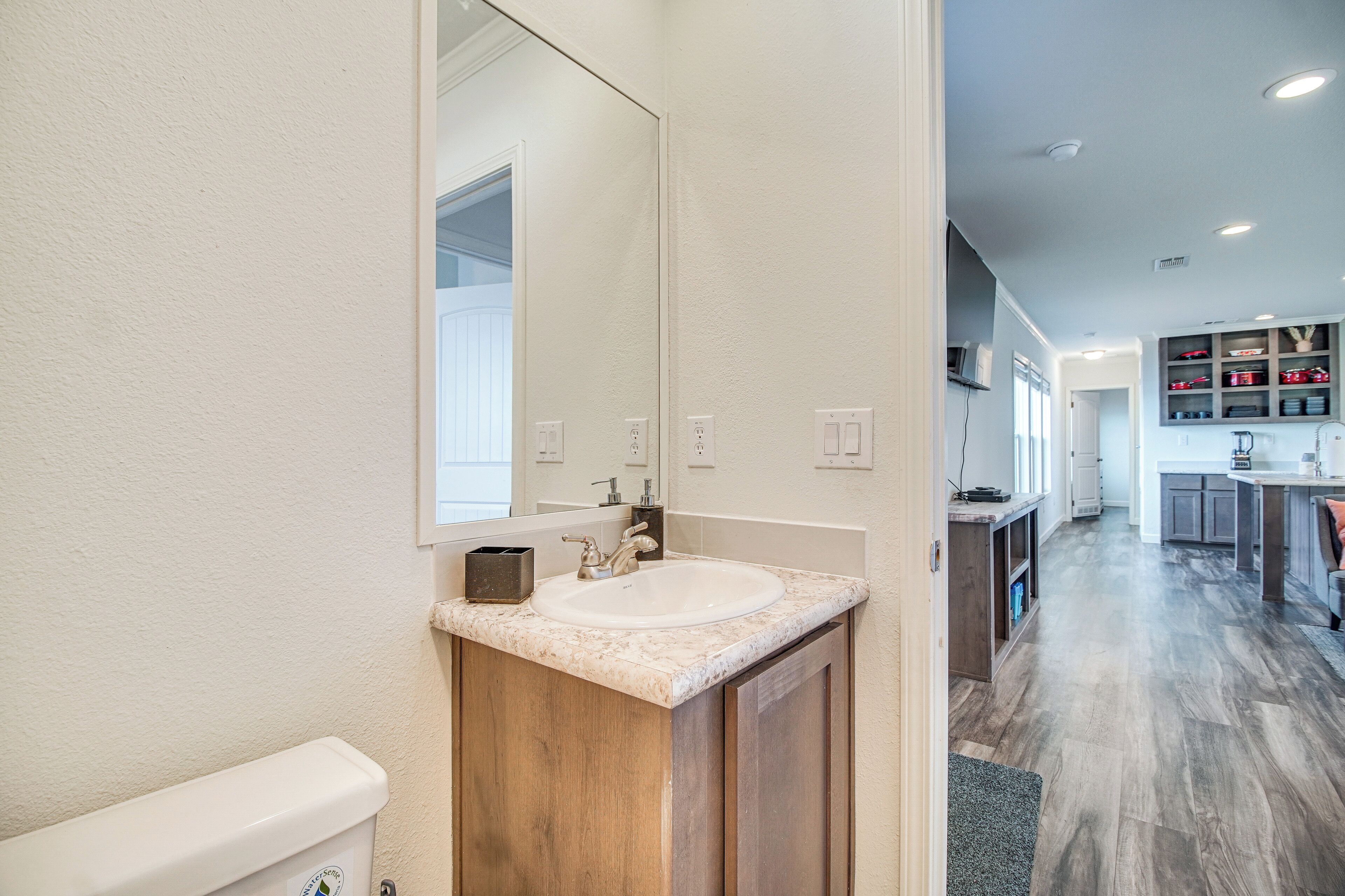 A bathroom with a sink, mirror, and wooden cabinet.