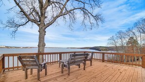 Une terrasse en bois avec deux bancs donnant sur une étendue d’eau.