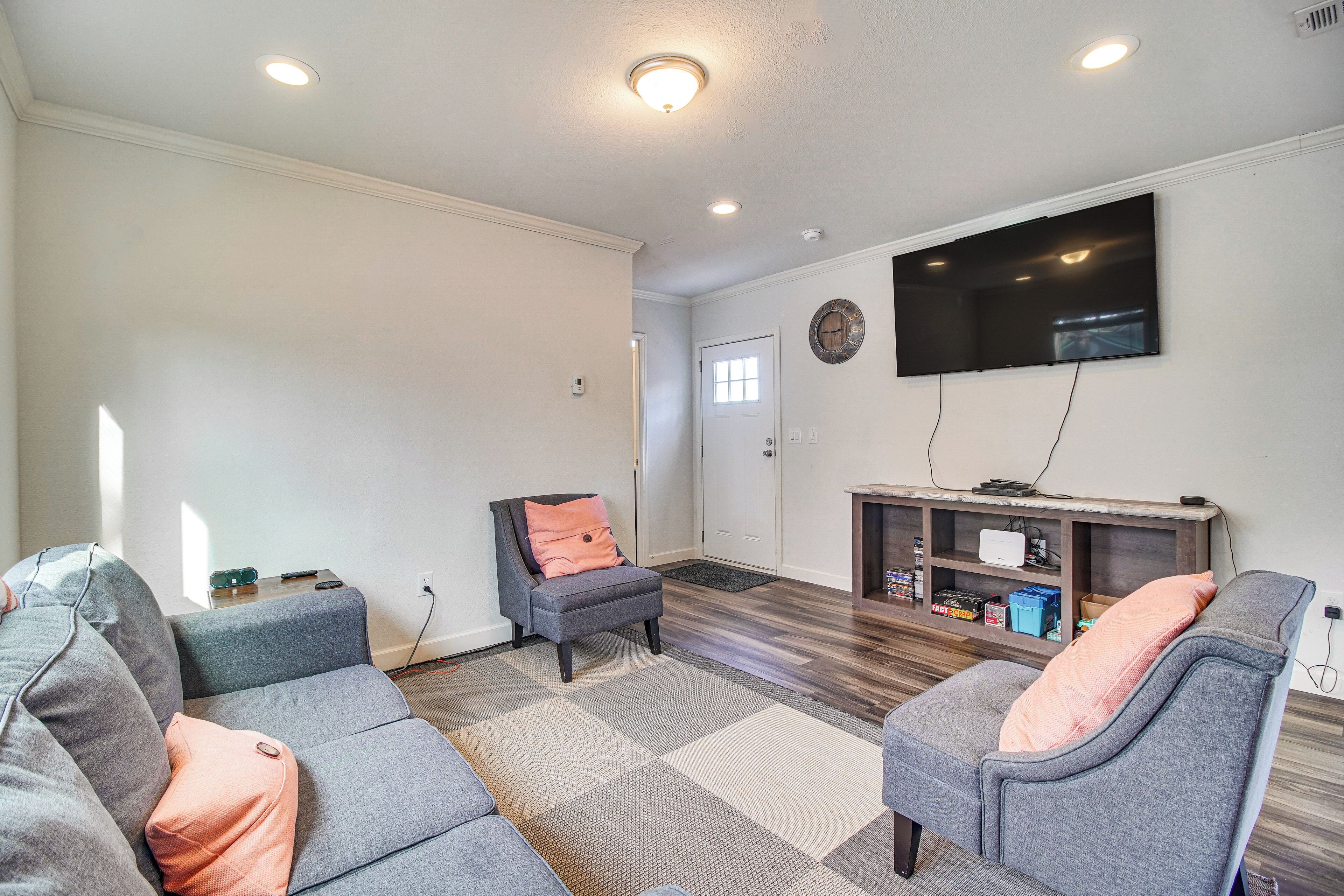 A living room with a grey sofa, a grey armchair, and a wooden entertainment unit with a flat-screen TV.