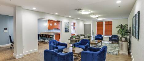 Un espacio habitable amplio, con una cocina al fondo, que incluye sillones azules y una mesa de centro.