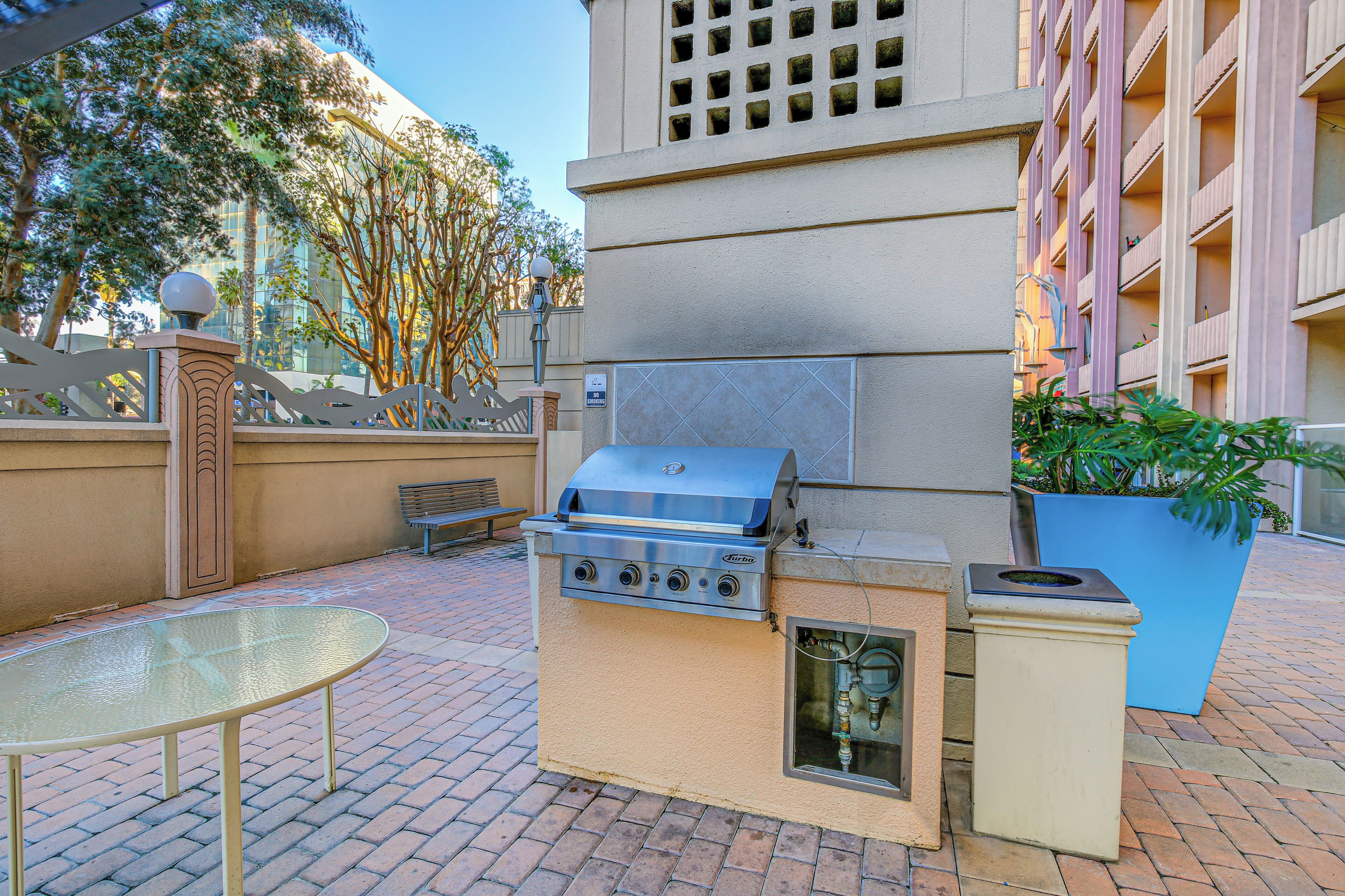 Cocina exterior con una parrilla, una mesa y un bote de basura.