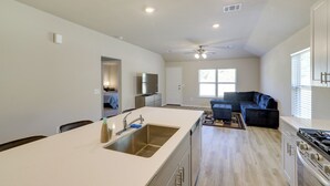 A modern kitchen with a central island, built-in appliances, and a dining area with a large table. - Brand New Spring Home < 1 Mi to Old Town! (Spring)