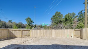 A fenced outdoor area with a dirt ground, a wooden fence, and a utility pole with wires. - Brand New Spring Home < 1 Mi to Old Town! (Spring)