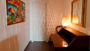 En hall med en träbänk, en lampa och en tavla på väggen.