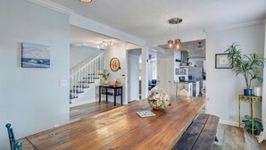 A spacious kitchen with modern appliances, a wooden dining table with a centerpiece, and a staircase leading to another level. - 0.1 Miles to Beach • Pet Friendly •  Walk to King & Prince • 2 Master Suites (St Simons Island)